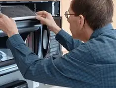 Appliance repair technician replacing a microwave vent filter in Worcester, MA