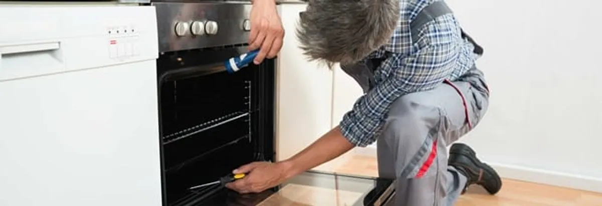 Oven repair technician inspecting and servicing an electric oven in Worcester, MA