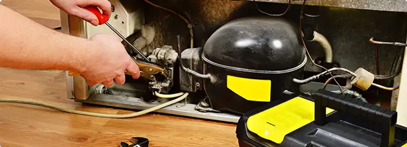 Refrigerator repair technician fixing the compressor and wiring in Worcester, MA